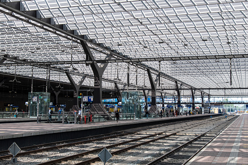 Rotterdam, the Netherlands-June 2022; View from one of the platforms of futuristic Centraal Station over platforms and train tracks with the solar panel roof casting shadows on the platforms