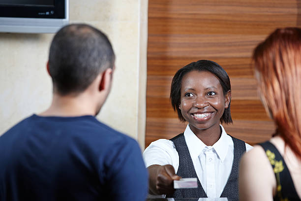 istock Hotel receptionist smiling holding out room card 155596704