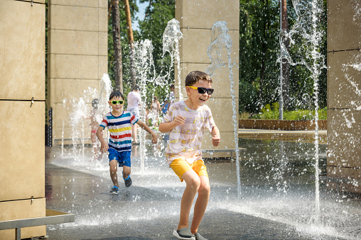Child plays and gets wet in the city fountain