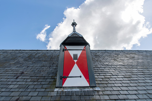 Gouda, The Netherlands-June 2022; Low angle close up view of gable dormer with red and white shutter on roof of St John's Church