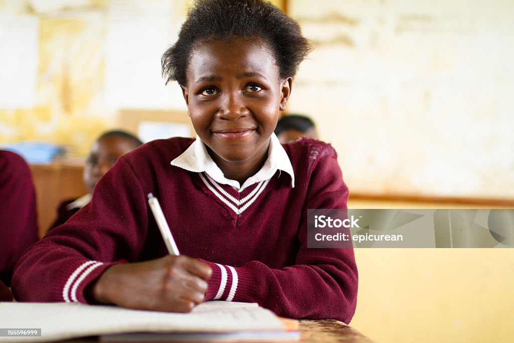 Young South African girl in classroom South African girl (from the Xhosa tribe) works on her studies at an old worn desk in a class room in the Transkei region of rural South Africa. Africa Stock Photo