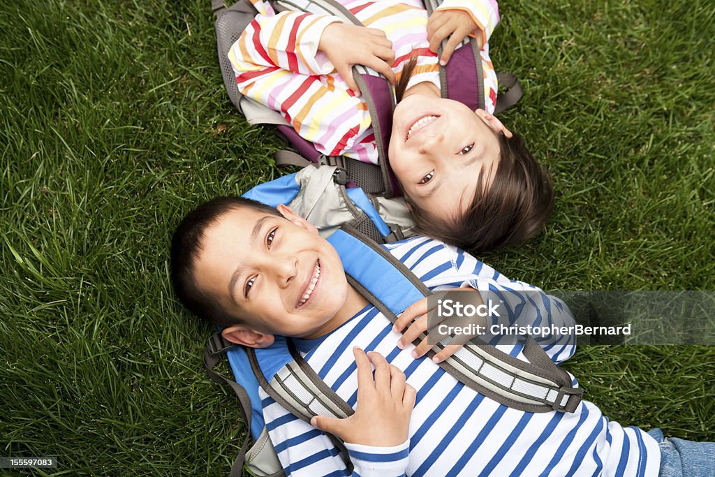 Młody chłopiec i dziewczynka leżąc na trawie w szkole - Zbiór zdjęć royalty-free (Powrót do szkoły)
