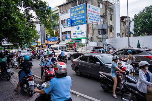 Ho Chi Minh, Viet Nam - 30 May 2023: Crowded, dense scene of city traffic at rush hour, crowd wearing helmets, traveling by motorbike, red light stop in tension, Vietnam