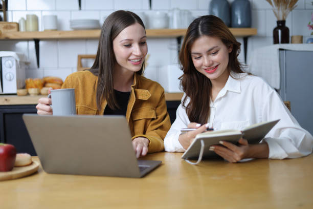 istock Two female students are happy while working on laptop and reading tutorial materials in home. 1555970901