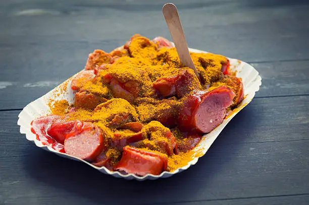 German national specialty - Currywurst - a sausage with hot sauce and curry powder, served in a paper tray with wooden fork.