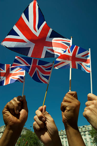 istock Hands Hold Union Jack Flags Waving in Blue Sky 155598105