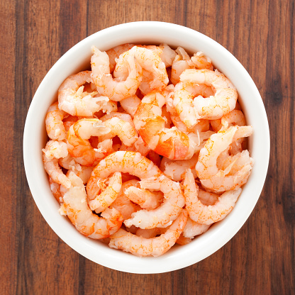 Top view of white bowl full of cooked shrimp