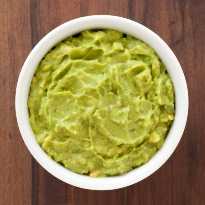 Top view of white bowl full of mashed avocado