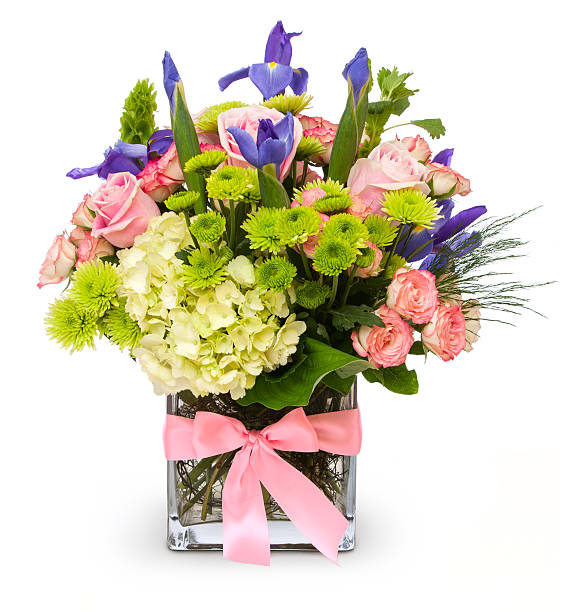 Colorful Floral Bouquet in Glass Vase with Pink Ribbon Isolated Straight on view of an isolated photograph of a glass square vase of colorful flowers in greens, pinks and purples, adorned with a pink ribbon around the vase. Canon 5D MarkII. flower arrangement stock pictures, royalty-free photos & images