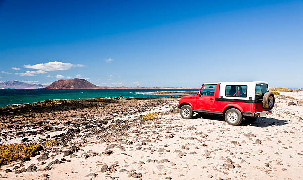 Red Jeep on Volcanic seascape. Fuerteventura stock photo