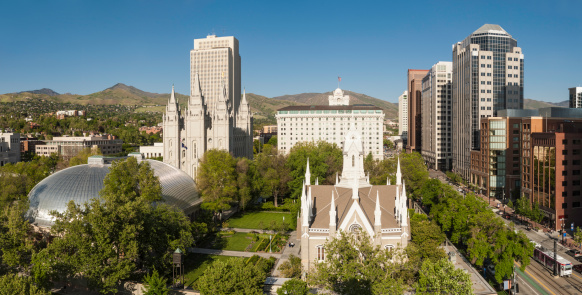 High angle vista over the iconic landmarks of downtown Salt Lake City, the Mormon Tabernacle, Salt Lake Temple, Temple Square, church office buildings and the high rises of downtown under clear blue panoramic skies, Utah, USA. ProPhoto RGB profile for maximum color fidelity and gamut.