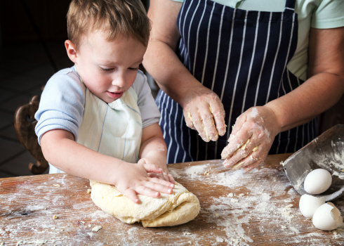 Little boy making bread with his grandma.