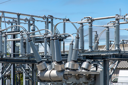 Close up view of some high-voltage bushings on a utility transformer at an electrical substation which allows an electrical conductor to pass safely through a conducting barrier