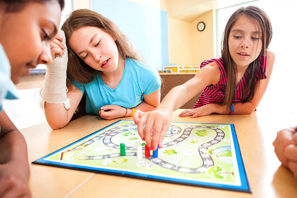 jovens alunos jogando um jogo de ensino - leisure games dice indoors table - fotografias e filmes do acervo