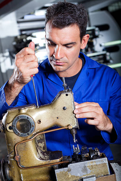 istock mechanic repairing industrial sewing machine 155599230