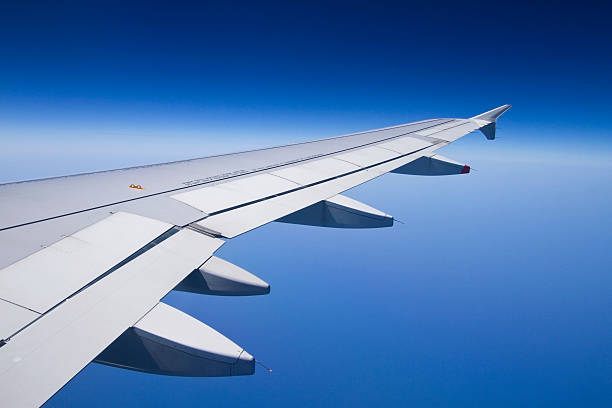 The wing of an airplane with a clear blue sky stock photo