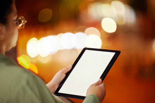 istock Woman, hands and tablet with mockup at night in city for communication, networking or browsing outdoors. Hand of female person or freelancer working late with technology display in an urban town 1555993830