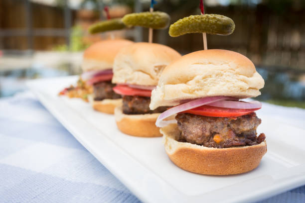 Three Slider Mini-Burgers on a plate outside at a picnicThree Slider Mini-Burgers on a plate outside at a picnic