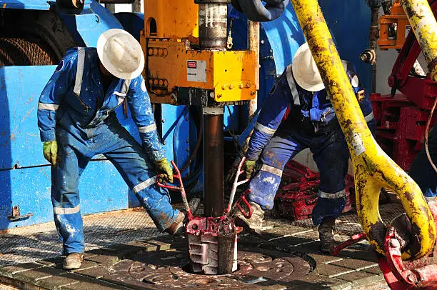 Drilling rig workers preparing to make a connection during drilling operation.