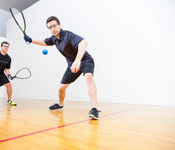 Men Playing Racquetball Two men playing racquetball on court. Shot at 1/100 of a second shutter speed to create a slight blurred motion to reveal the fast motion of racquetball. squash sport stock pictures, royalty-free photos & images