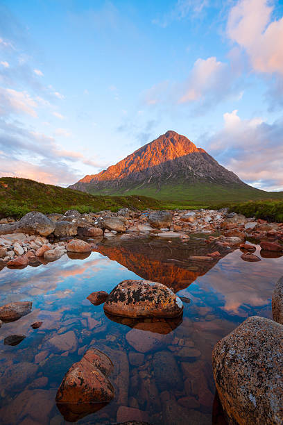 Buachaille Etive Mor and the River Coupall. Morning sunlight at dawn illuminates Buachaille Etive Mor (Stob Dearg).  The river in the foreground is the River Coupall.  Buachaille Etive Mor, translated from Scottish Gaelic as The Great Herdsman of Etive is classified as a munro, being 3353 feet in height.  Located at the head of Glen Etive, this beautiful mountain is a fabulous precursor to Glencoe a further couple of miles along the A82. buachaille etive mor photos stock pictures, royalty-free photos & images