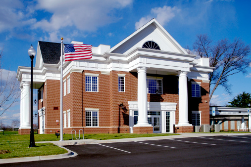Exterior of a Bank/Office Building with an American Flag against a beautiful blue sky.