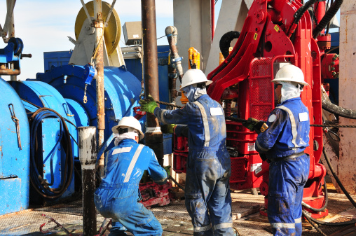 Drilling rig workers making a connection during drilling operation.