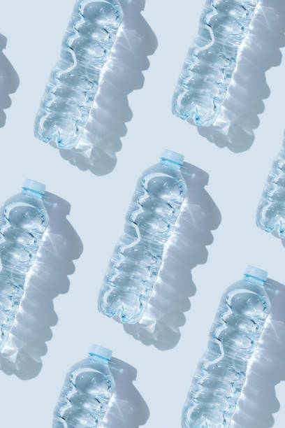 istock Minimal Pattern Plastic bottles water at sunlight with shadow on blue, aesthetic top view. Distilled drinking water. Pollution, environmental protection. Eco trend to reduce disposable plastics 1556013745