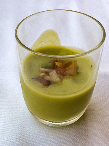 A small welcome drink of a cold Amuse Bouche containing a cold spicy  avocado soup