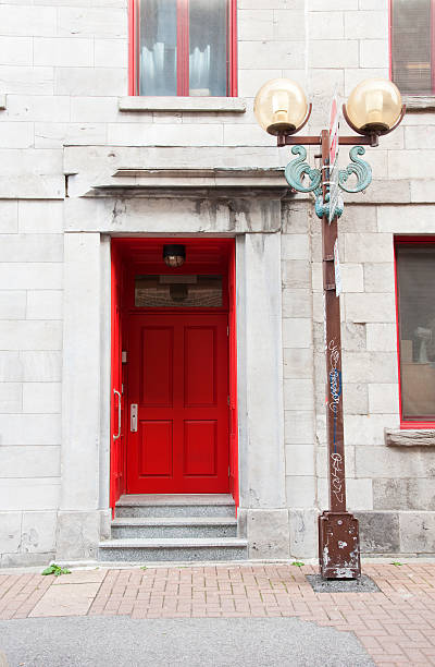 The entrance to an old building in Montreal's chinatown with a red door and an old style streetlight.