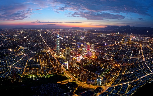 Aerial skyline of Downtown Taipei at sunset, the capital of Taiwan, with 101 Tower standing out among modern skyscrapers in Xinyi Commercial District and city lights dazzling under blue twilight sky