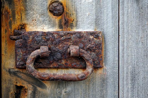 Old steel door lock on an old battered door, close-up.