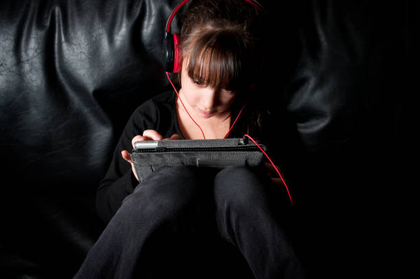 istock Girl using headphones playing with a digital tablet 155601986