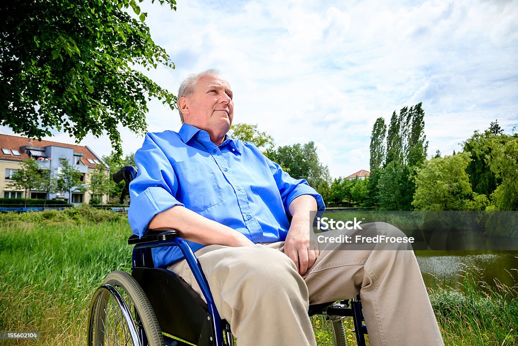 Uomo anziano seduto su una sedia a rotelle - Foto stock royalty-free di 70-79 anni