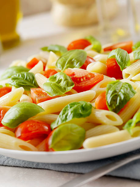 Pasta with Fresh Basil and Tomatoes Penne with Fresh Basil, Tomatoes and a Glass of Chianti -Photographed on Hasselblad H3D2-39mb Camera cooked selective focus vertical pasta stock pictures, royalty-free photos & images