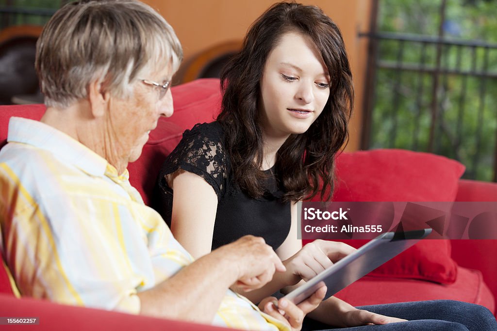 Adolescente spiegare l'uso del digital tablet di donna anziana - Foto stock royalty-free di Adolescente