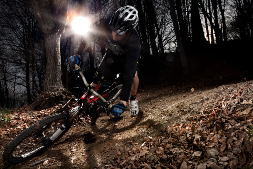 Downhill enduro mountain bike curve in the woods. Motion blur, real flash flare (and real sun flare) effect.