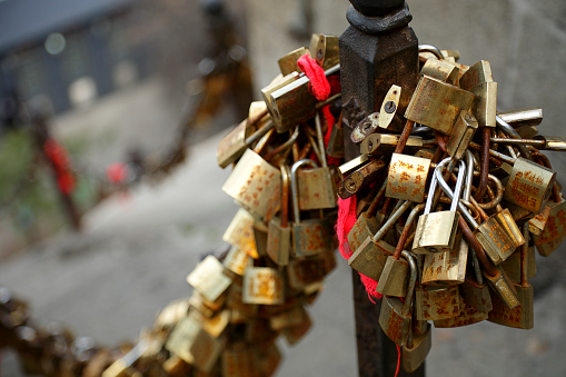 Single red padlock with heart on it connected to a chain, brown blurred background, horizontal