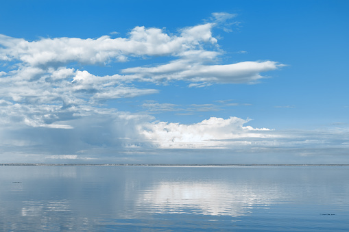 Nature picturesque landscape, clouds reflected on water surface, windless summer weather, tranquil blue trend sky background, mirroring sky on water, white blue nature gradient, aesthetic skyline