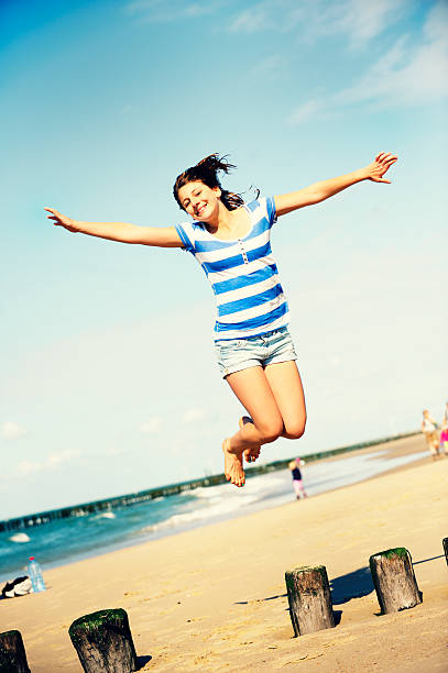 mädchen springen am strand - arms outstretched teenage girls jumping flying stock-fotos und bilder