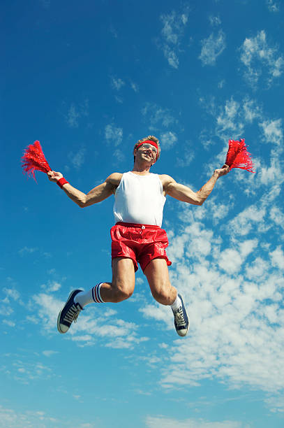 male-cheerleader-does-a-nerdy-jump-with-pom-poms.jpg