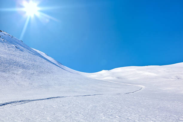 Landscape of East Greenland with mountains, snow, blue sky and sun
