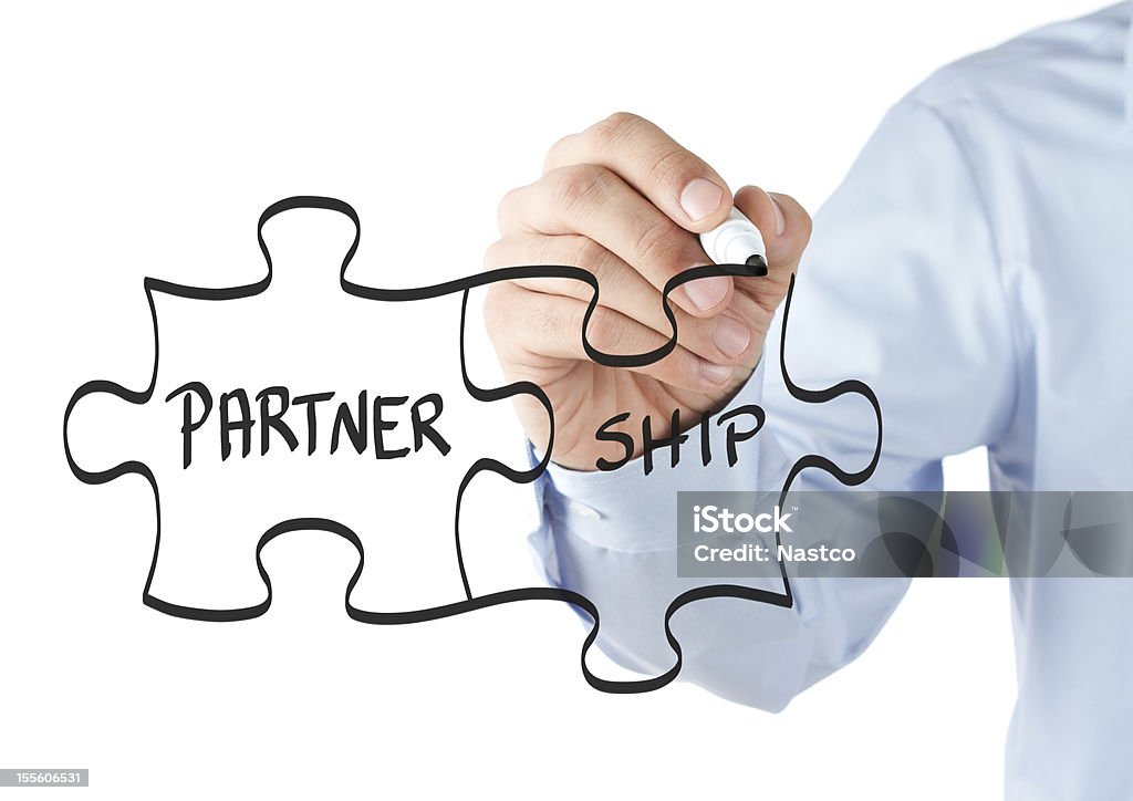 Partnership puzzle concept Human hand drawing partnership puzzle on the whiteboard Partnership - Teamwork Stock Photo