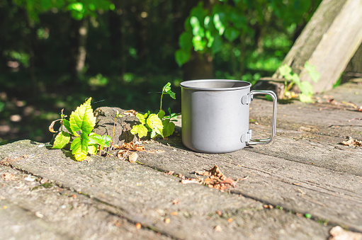 Metal cup on a wooden table in nature. Tea in nature