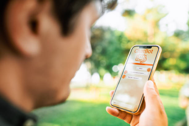 istock Man talking to a chatbot with voice commands using smartphone. Robot service assistant,  modern artificial intelligence, futuristic innovation and technology concept. 1556104744