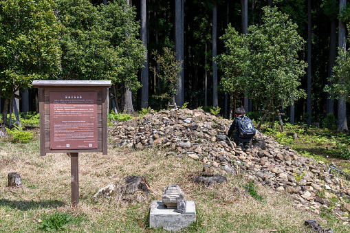 Tanabe, Wakayama, Japan-4 April 2023; Haraido Stound mound along footpath or Kumano Kodo pilgrimage trail and UNESCO heritage site in thick forested area with small boy on the pile of stone