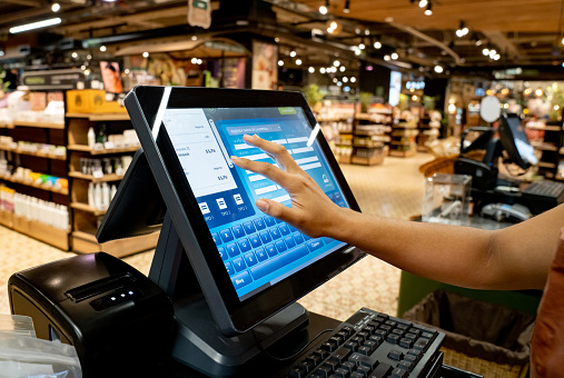 Close-up on a cashier registering products at the supermarket using a touch screen