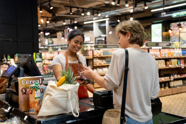 mulher fazendo um pagamento sem contato no supermercado - groceries women bag customer - fotografias e filmes do acervo