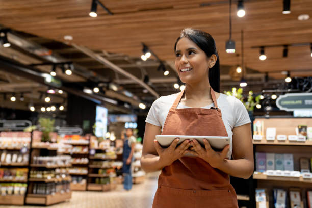 istock Saleswoman using a digital while working at the supermarket 1556120391