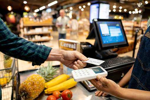 Close-up on a customer making a contactless payment with his credit card at the supermarket